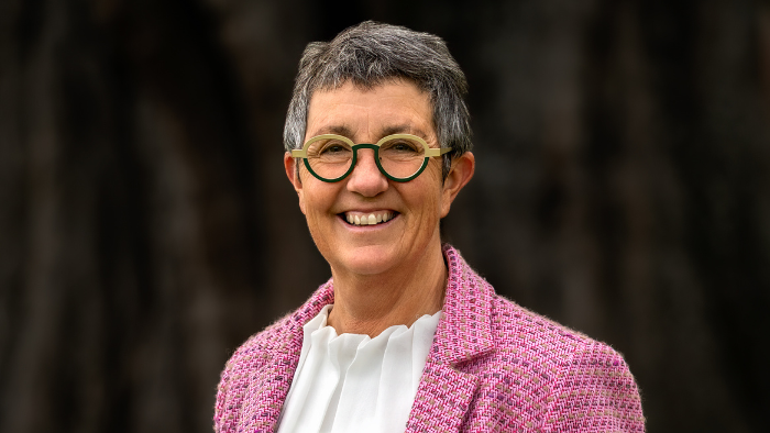 Leanne Southey smiles into the camera wearing a pink jacket with a dark neutral background Leanne Southey smiles into the camera wearing a pink jacket with a dark neutral background